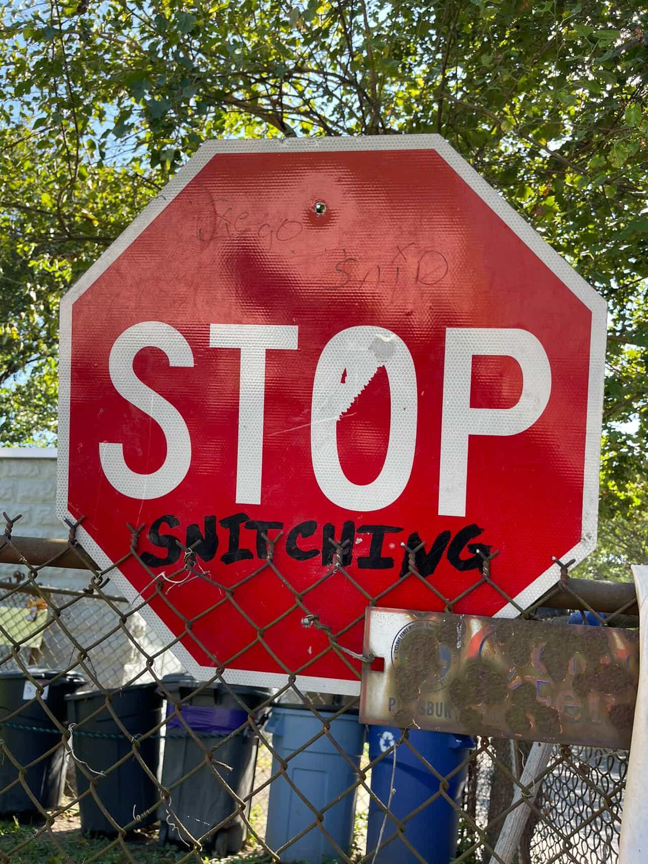 a red STOP sign, that someone has scrawled "snitching" on, to make it read "stop snitching"