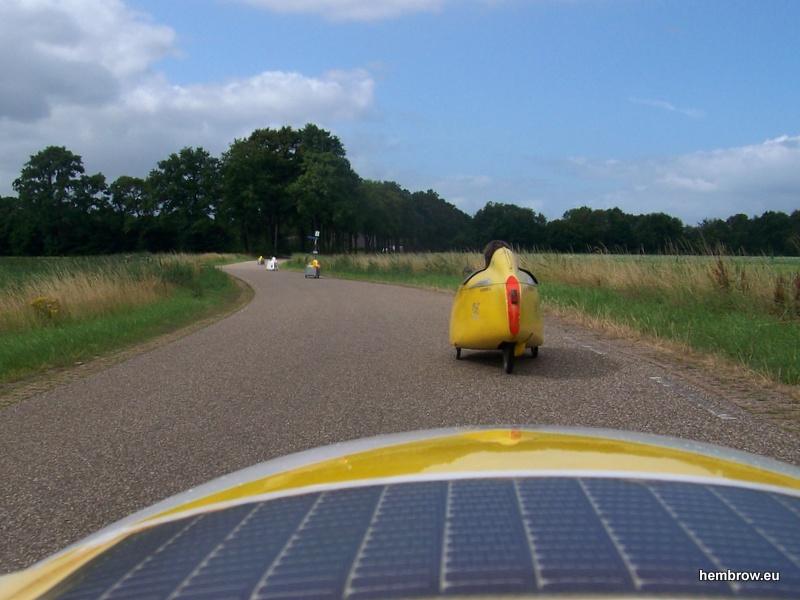 A line of velomobiles head along a country lane in Drenthe